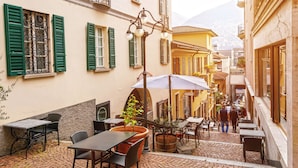A cobblestone courtyard with outdoor seating, a street lamp, and buildings with green shutters. - Ca' Melin with Balcony & Fireplace, Vezio, Switzerland (Vezio)