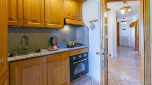 A kitchen with wooden cabinets, a granite countertop, a stove, and a sink. - Cervo Ski in - Ski out 200m, Livigno, Italy (Livigno)