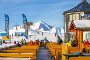 A ski resort with wooden benches and a building with a sloped roof. - Rubino Ski in, Livigno, Italy (Livigno)