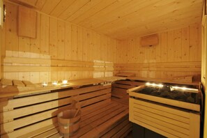 Eine Holzsauna mit Bänken, einem Steinkorb und einem Holzschrank.