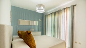 A bedroom with a bed, a bedside table, a mirror, and curtains. - Fantastic Duplex in Puerto Rico (Mogán)