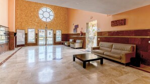 A spacious lobby with a marble floor, a large window, a sofa, and a reception desk. - Fantastic Duplex in Puerto Rico (Mogán)