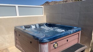 A hot tub with a wooden exterior and a blue interior, positioned against a tiled wall. - Fantastic Duplex in Puerto Rico (Mogán)