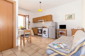 A compact living space with a kitchenette, a dining area, a sofa, and a TV.
