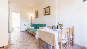 Un coin repas avec une table dressée pour quatre personnes, un canapé vert et deux tableaux encadrés accrochés au mur.