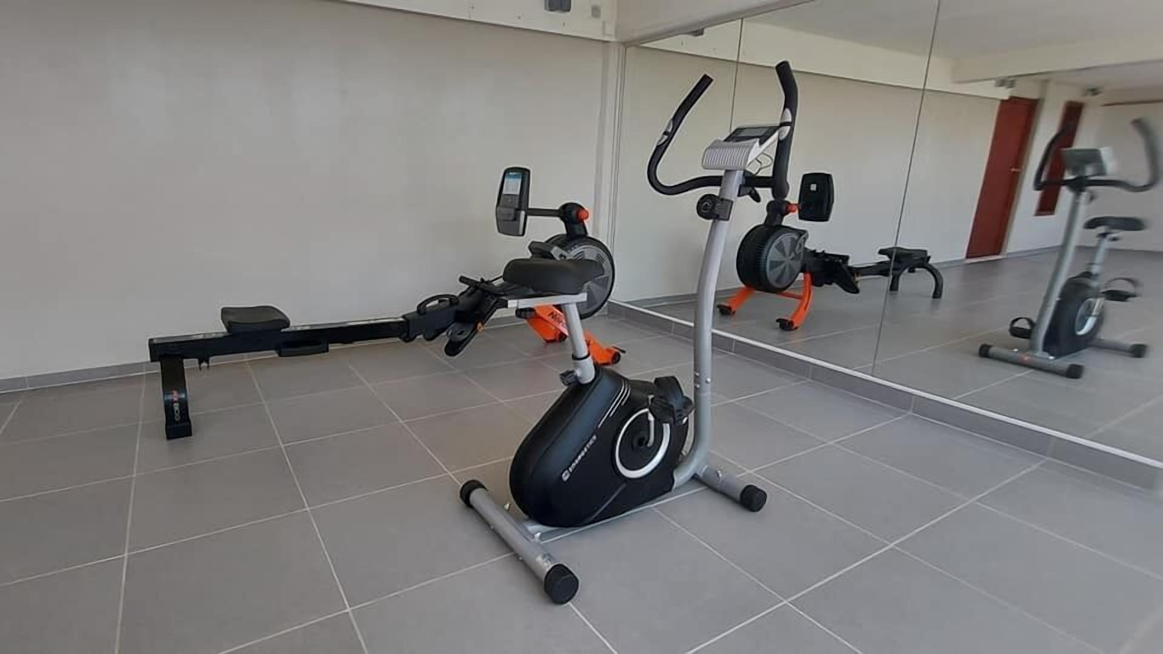 A gym with exercise equipment including a stationary bike, a treadmill, and a rowing machine.