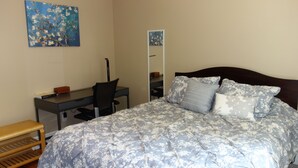 A bedroom with a bed, a desk, a chair, a mirror, and a bench. - The Better Half Duplex on 7th (Charlotte)