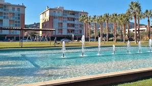 A public park with a fountain, palm trees, and a playground.