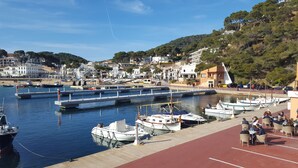 A marina with boats docked, a red walkway, and buildings in the background.
