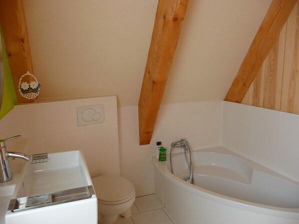 A bathroom with a white bathtub, a toilet, and a sink. - Finnhaus 200m from the Baltic Sea coast, sea view to Hiddensee + Moen, free WLAN (Dranske)