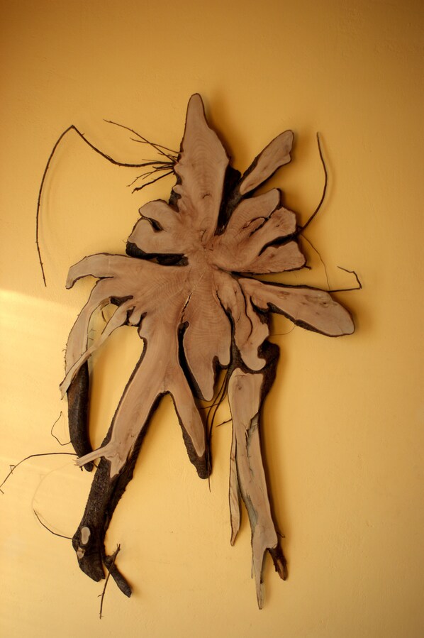 Una escultura de madera con un diseño natural y orgánico sobre un fondo amarillo liso.