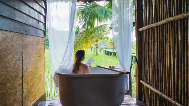 A bathtub in a rustic setting with a view of a lush garden.