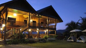 A two-story wooden building with balconies, a staircase, and a well-lit entrance.