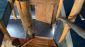 A wooden staircase with a rustic design, leading to a room with a blue wall and a window.