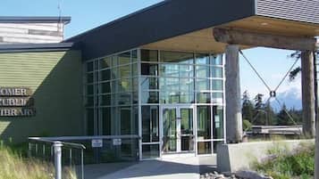 Exterior de la Biblioteca Pública de Homer, con fachada de vidrio moderna y un acceso cubierto.