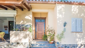 Una casa con puerta de madera, un pequeño porche con escalones y plantas en macetas.