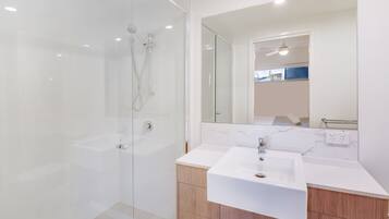 A modern bathroom with a glass-enclosed shower, a white sink, and wooden cabinets.