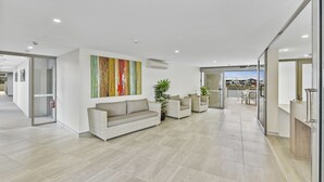 A spacious living area with a sofa, armchairs, and a large abstract painting on the wall.