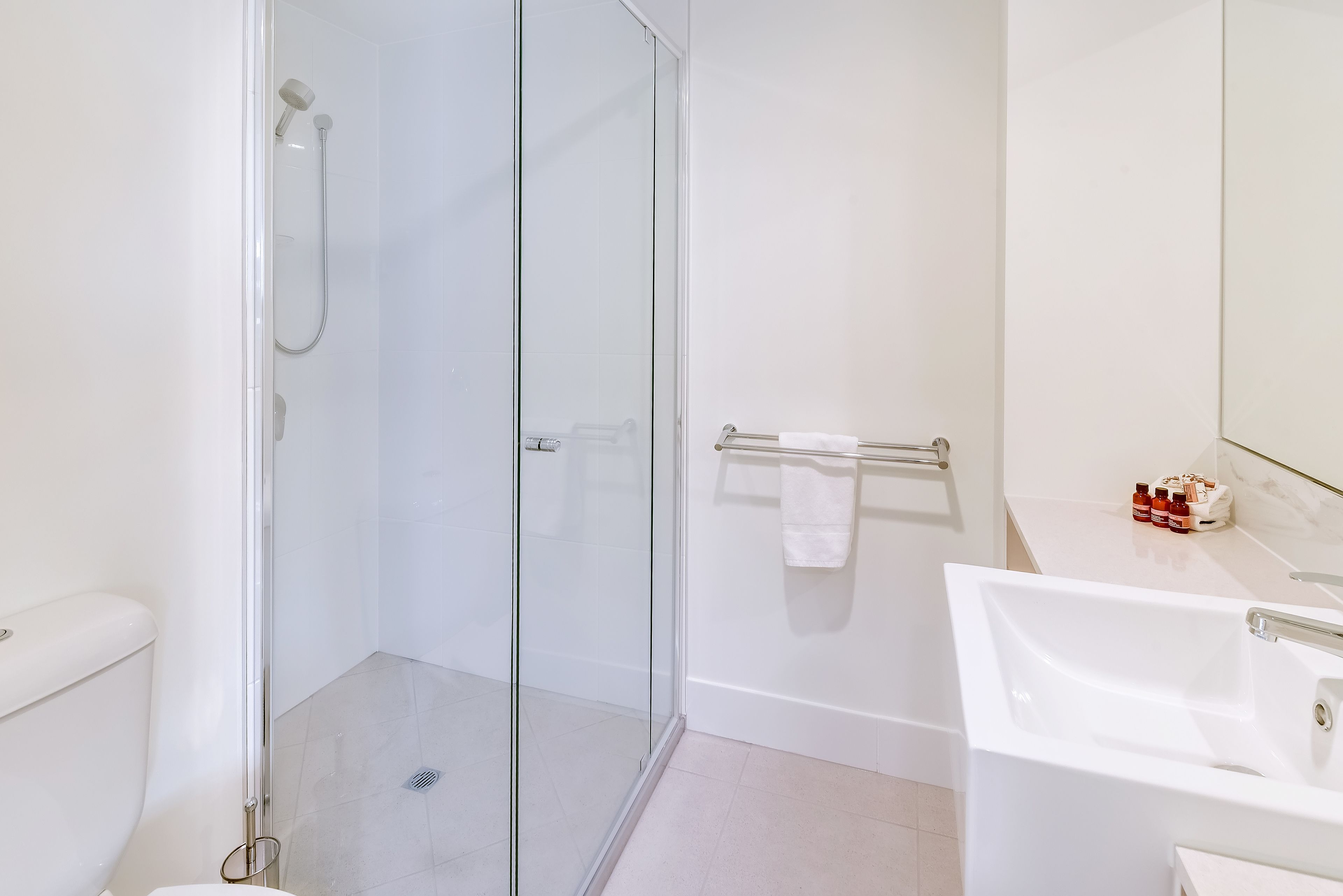 A modern bathroom with a glass-enclosed shower, a white sink, and a toilet.