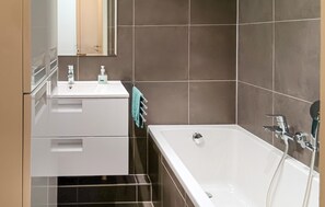 Une salle de bain moderne avec un lavabo blanc, un miroir et une baignoire.