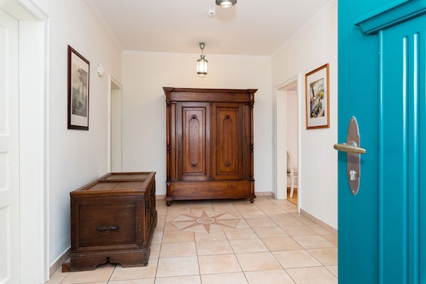 A hallway with a wooden cabinet, a blue door, and a tiled floor. - Apartment, 4 rooms, hallway, 80sqm, 2-(4)pers. (Fehmarn)