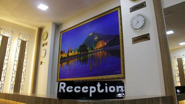 A reception area with a large framed painting of a night scene, clocks labeled 'LONDON' and 'BANGKOK', and a sign that reads 'Reception'. - Orient Hotel (Mandalay)
