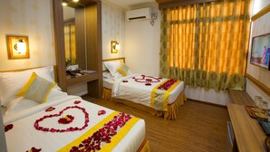 A hotel room with two beds, a desk, and a window with curtains. - Orient Hotel (Mandalay)