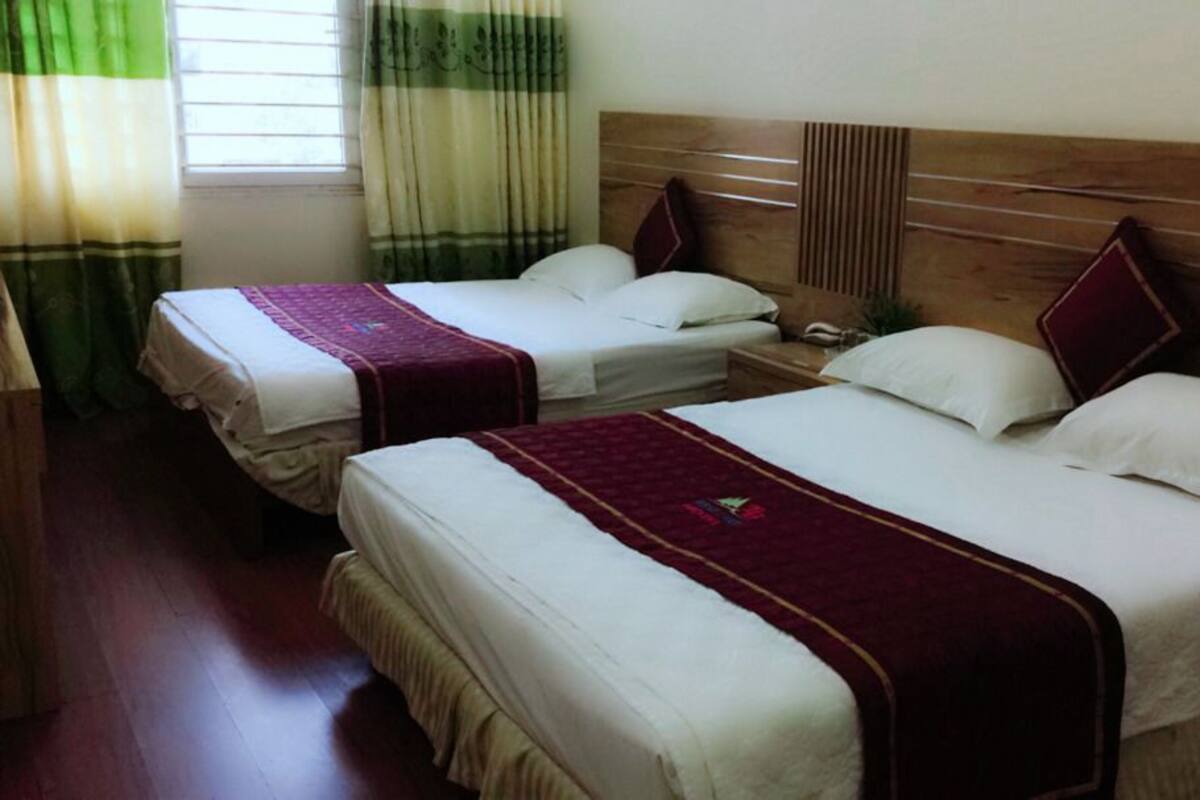A hotel room with two beds, each with a wooden headboard, white bedding, and a red throw blanket.