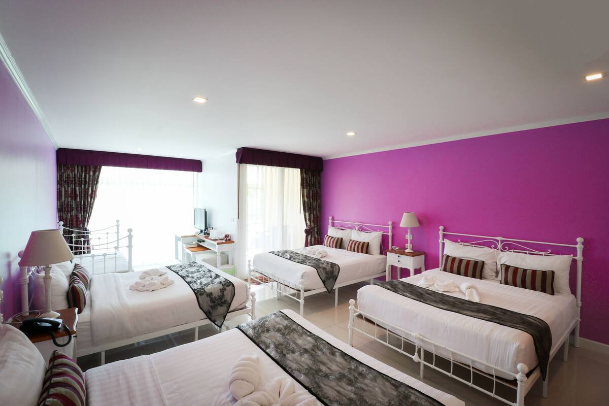 A hotel room with two beds, a desk, a chair, and a window with curtains.