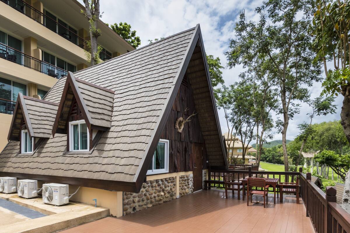 A modern building with a sloped roof and a balcony with outdoor furniture.