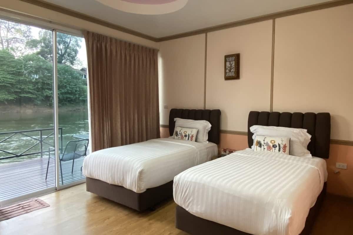 A hotel room with two beds, a large window with a view of a body of water, and a ceiling light.
