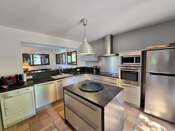 A modern kitchen with stainless steel appliances, a central island, and a view of the outdoors.