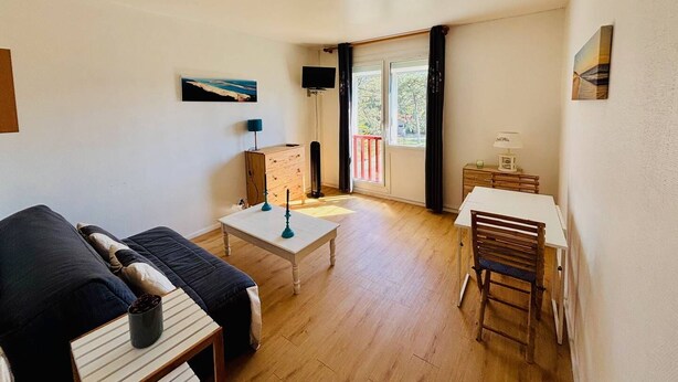 Een kamer met een bed, bureau, stoel, televisie en raam met gordijnen.