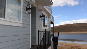 Une maison avec un porche, un escalier menant à une terrasse, et une vue sur un lac.
