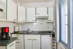 Kitchen features white cabinetry, dishwasher, and stainless steel sink.