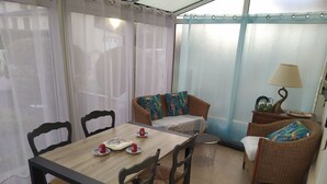 A dining area with a wooden table, four chairs, and a sofa with patterned cushions. - Charming south facing house completely renovated with garden (Dives-sur-Mer)