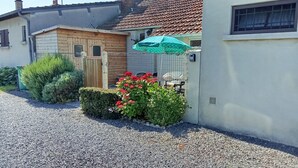 A residential property with a gravel driveway, a wooden gate, a green umbrella, and a small garden with red flowers. - Charming south facing house completely renovated with garden (Dives-sur-Mer)