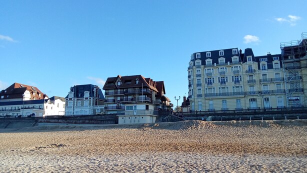 A coastal building with multiple balconies, a sandy beach in the foreground, and a clear blue sky. - Charming south facing house completely renovated with garden (Dives-sur-Mer)