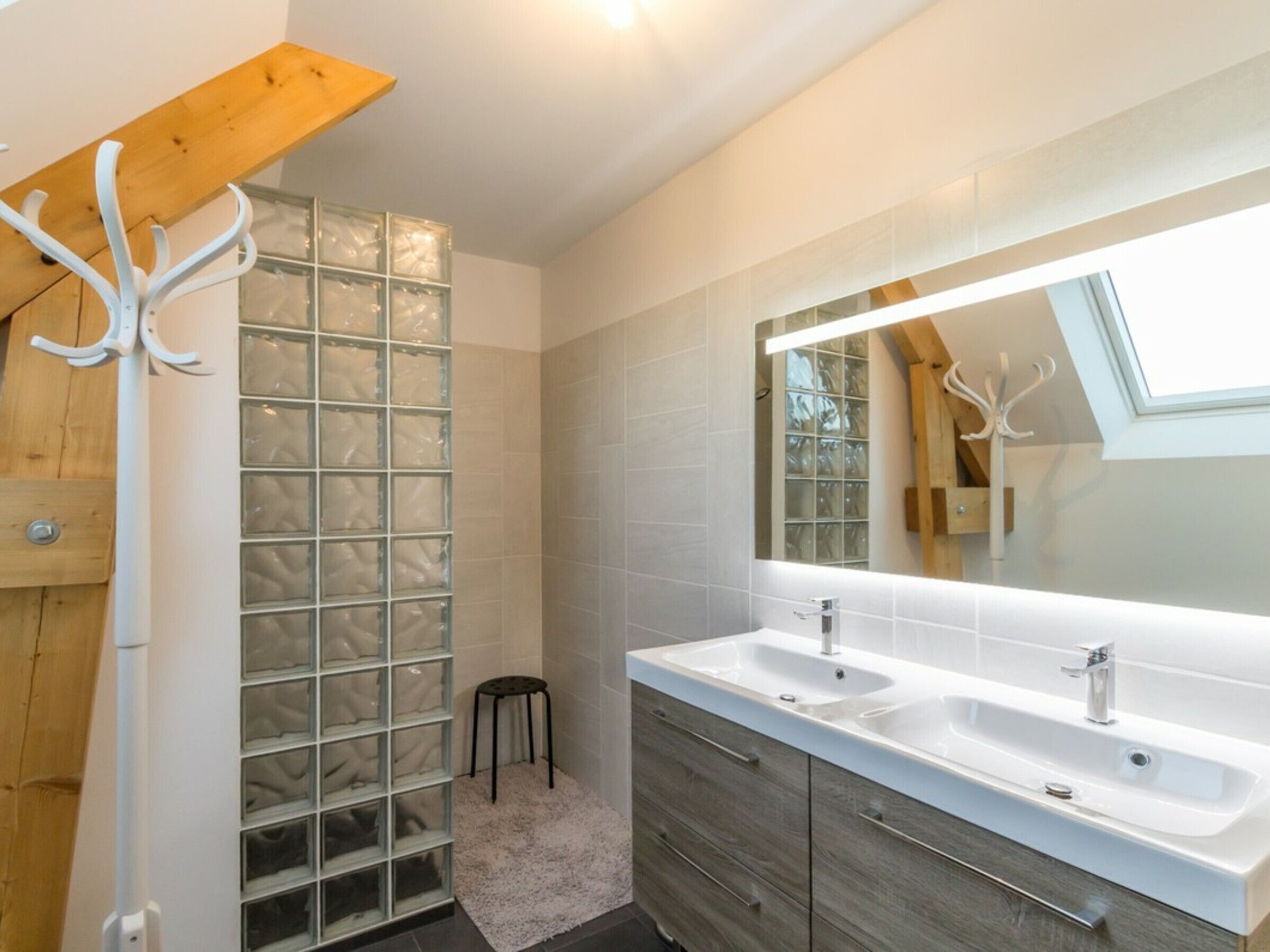 Un bagno moderno con un grande specchio, due lavabi e una cabina doccia in vetro.