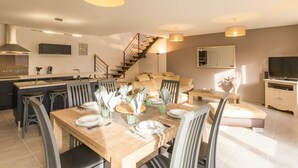 A modern kitchen with a dining area, a staircase, and a living room with a sofa and TV. - Independent house facing the sea with balcony and terrace (Saint-Vaast-la-Hougue)