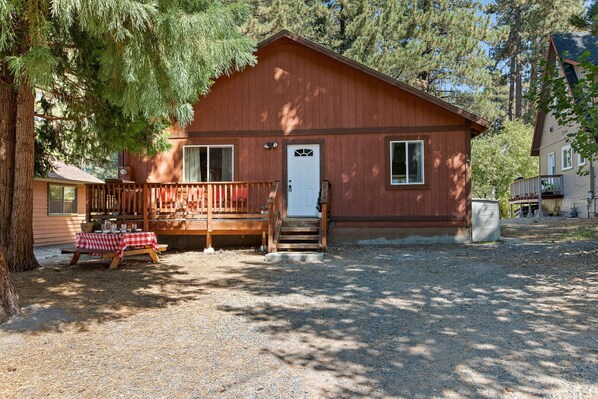 A wooden cabin with a porch, a front door, and a picnic table set up outside.