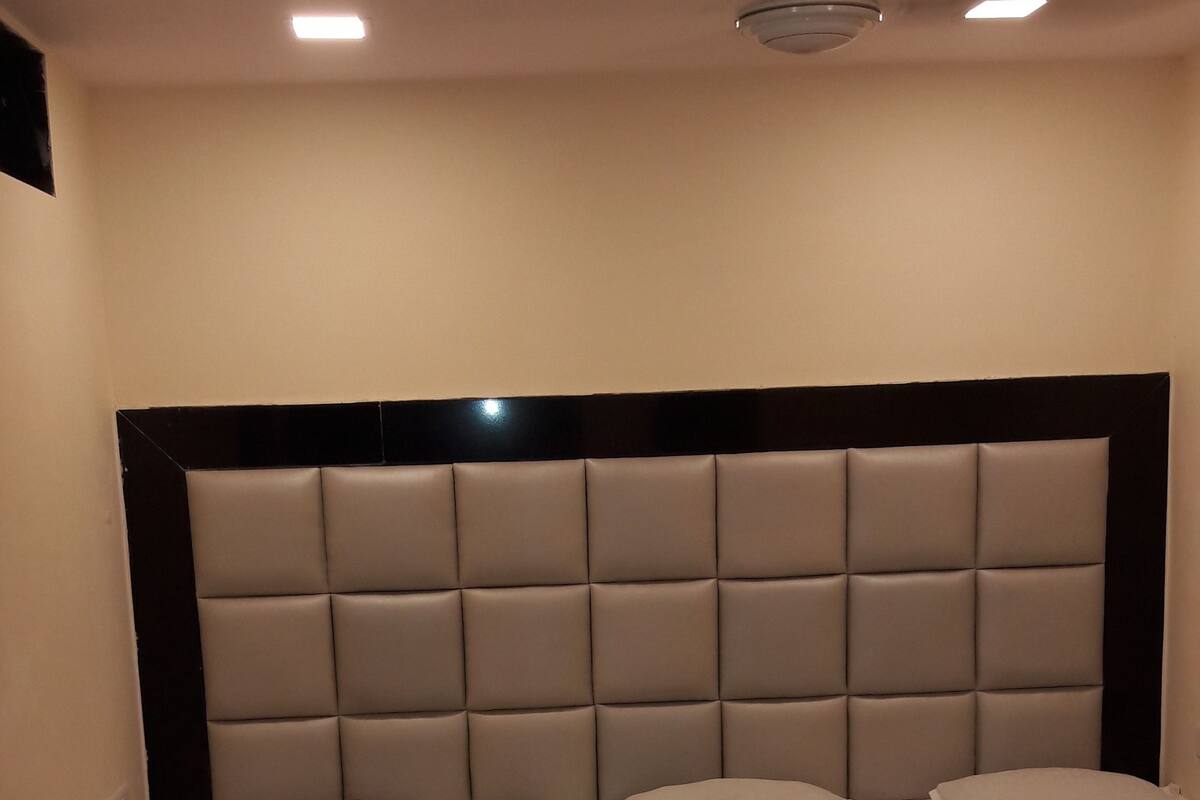 A hotel room with two beds, each with a headboard and pillows.