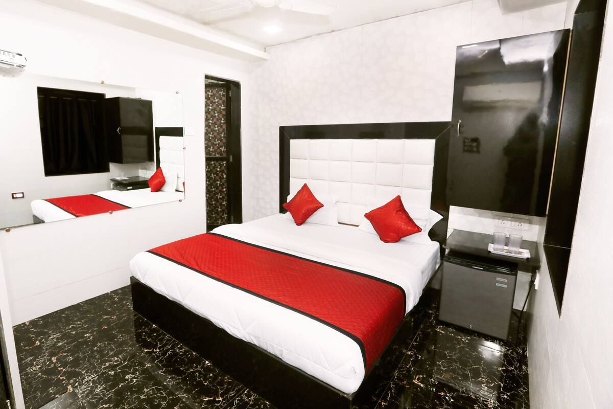 A hotel room with a bed, a mirror, a wardrobe, and a television.