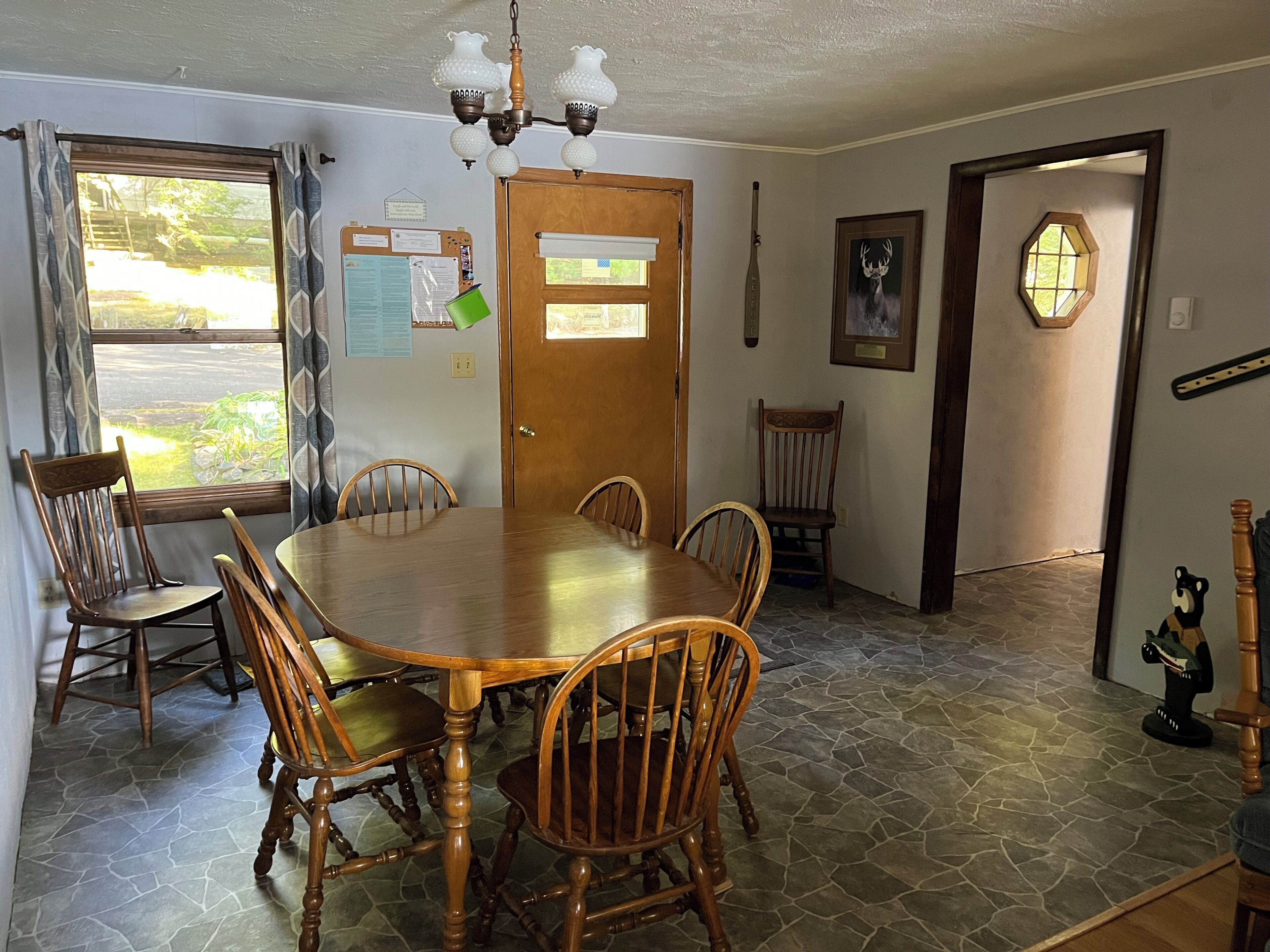 A dining room with a wooden table and chairs, a chandelier, and a door with a window.