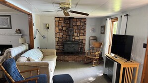 A cozy living room with a stone fireplace, a television, and comfortable seating. - 
 Enjoy Our Cabin And Sunsets, On Peaceful , Non-Motorized  Lulu Lake (Shawano)