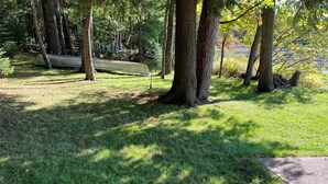 A grassy area with trees and a canoe. - 
 Enjoy Our Cabin And Sunsets, On Peaceful , Non-Motorized  Lulu Lake (Shawano)