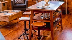 A cozy wooden cabin interior with a chandelier, a dining table with a silver trophy, and a large window with blinds. - Spacious, Private 3BR Suite: Steps to King (Charleston)