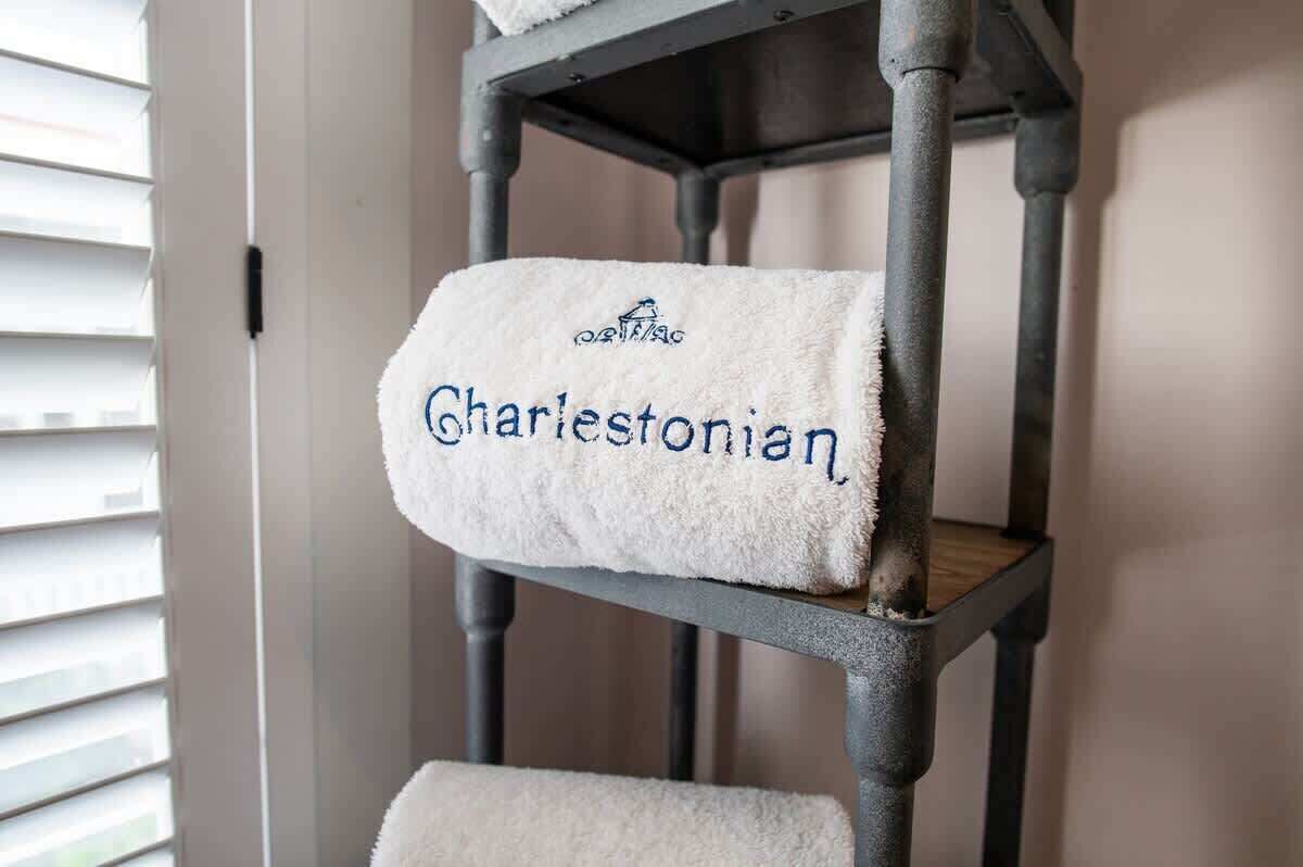 Une serviette sur laquelle est écrit le mot « Charlestonian », posée sur une étagère en métal.