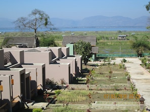 Área residencial com edifícios modernos, um jardim bem cuidado e vista para o mar e montanhas ao fundo.
