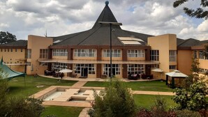 A building with a distinctive peaked roof, multiple windows, and a well-maintained lawn with outdoor seating areas. - Elysian Resort (Nairobi)